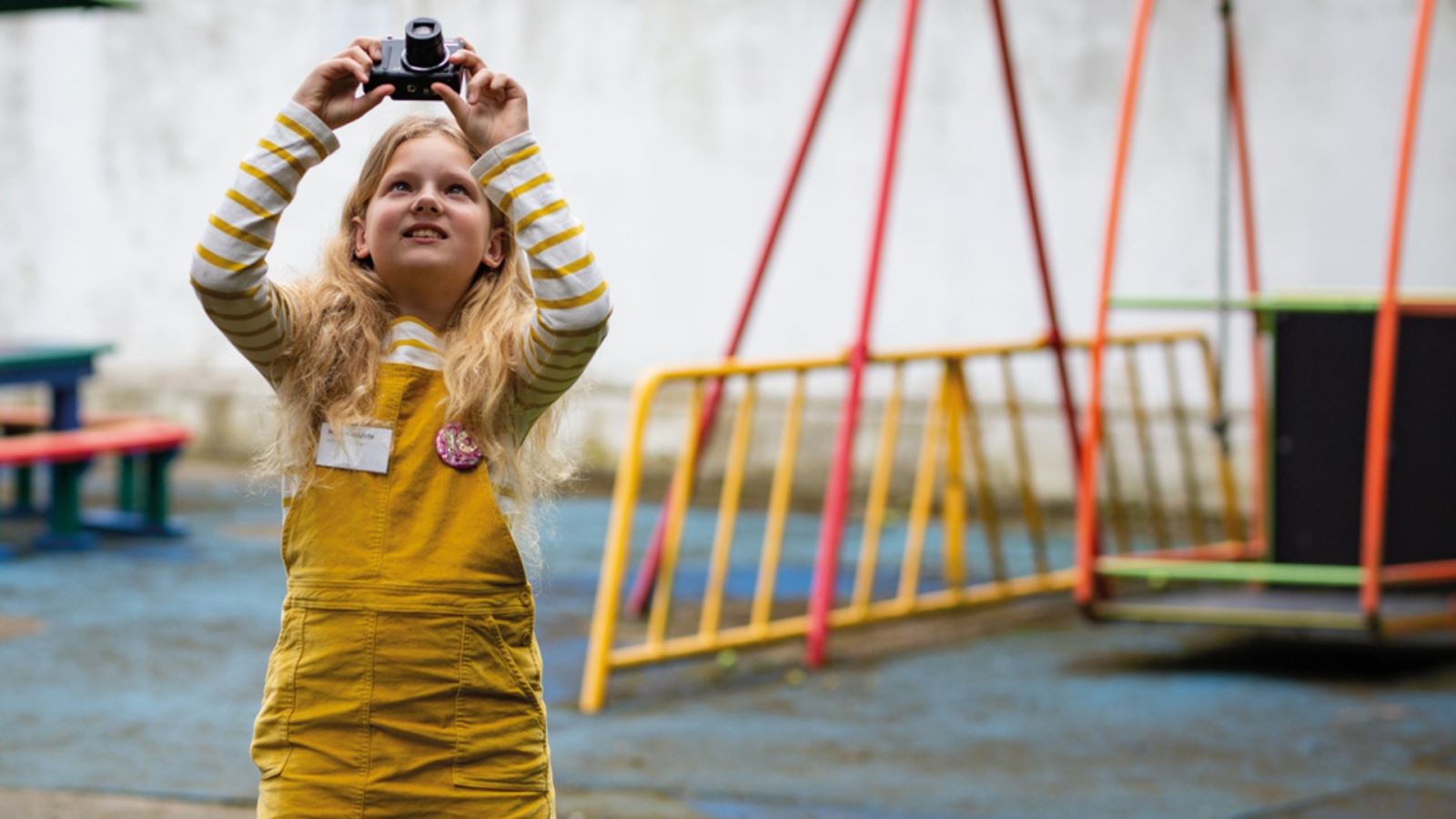 A little girl, in a yellow dress, take a picture